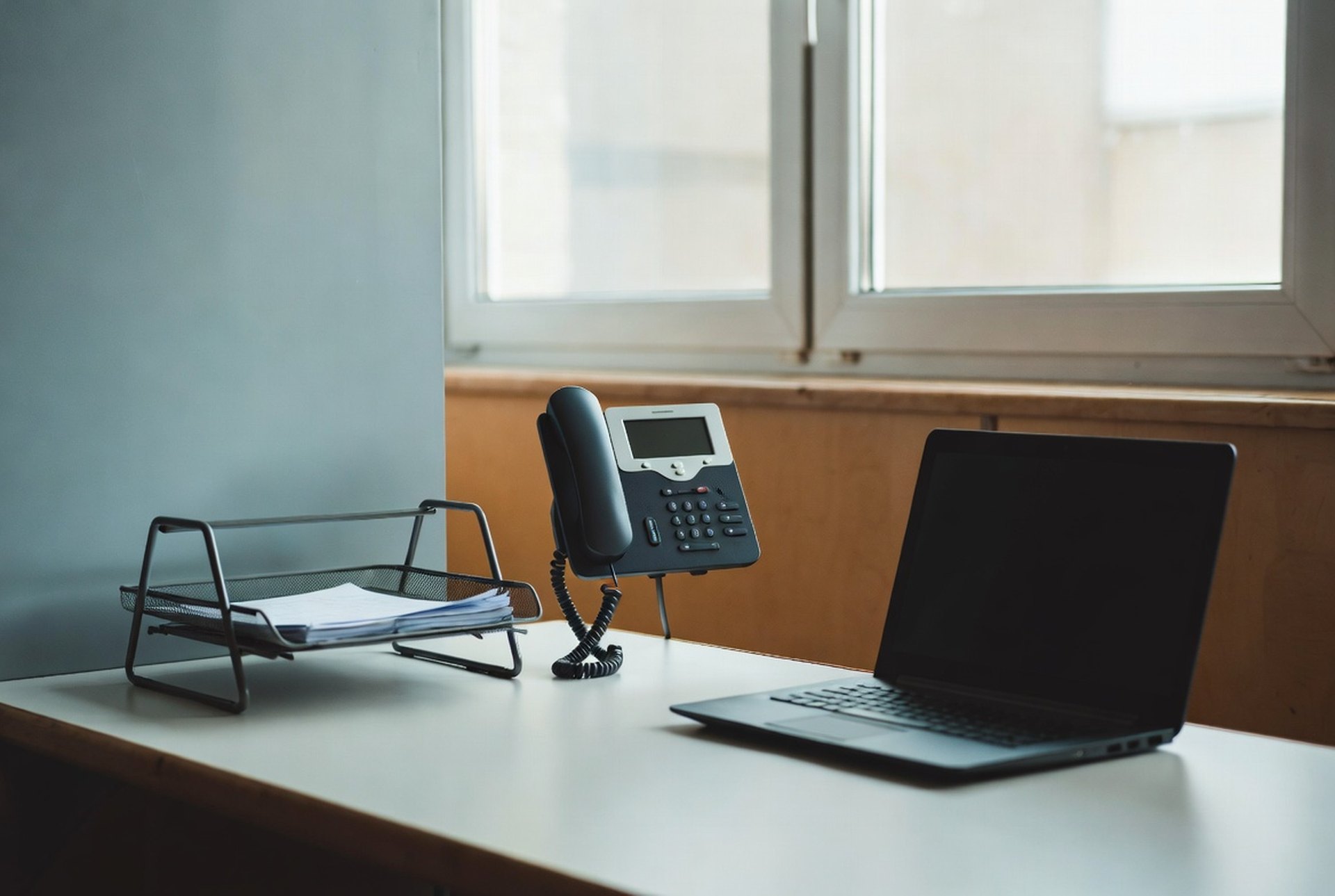 A clean medical office desk with an IP phone and a closed laptop