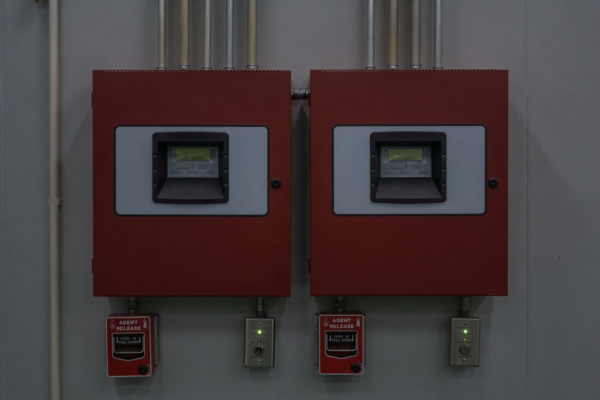 Two red fire suppression release control panels with manual pull stations on a mechanical room wall